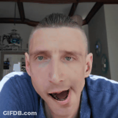 A Man In A Blue Shirt Is Making A Funny Face With His Mouth Open GIF