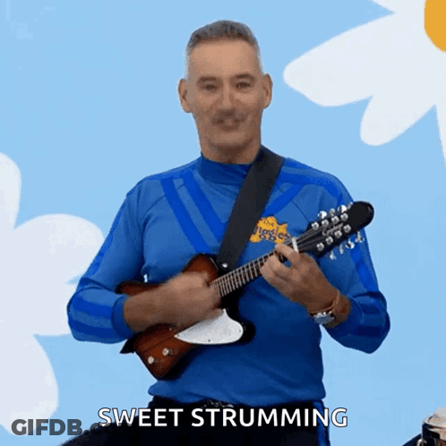 A Man In A Blue Shirt Is Playing A Guitar And Says Sweet Strumming In The Corner GIF