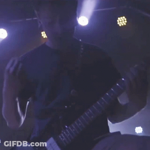 A Man In A Blue Shirt Is Playing A Guitar With The Letters H And I On The Neck GIF