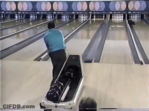 A Man In A Blue Shirt Is Playing Bowling On A Bowling Alley GIF