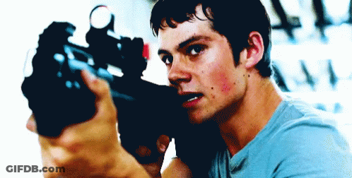 A Man In A Blue Shirt Is Pointing A Gun At Something GIF