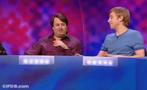 A Man In A Blue Shirt Is Pointing At Another Man In A Purple Shirt GIF