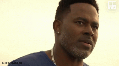 A Man In A Blue Shirt Is Praying With His Hands Folded In Front Of His Face GIF