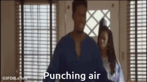 A Man In A Blue Shirt Is Punching Air While A Woman Stands Behind Him . GIF