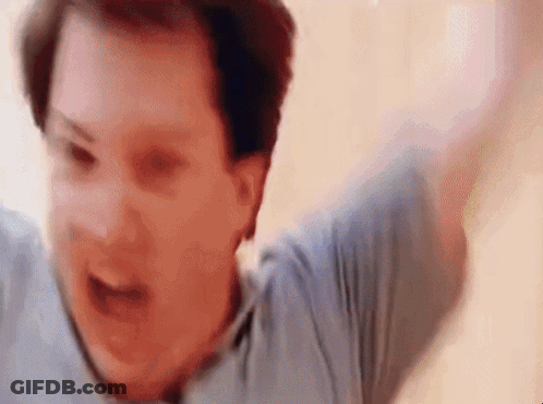 A Man In A Blue Shirt Is Screaming With His Arms Outstretched . GIF