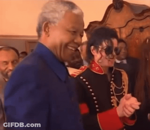 A Man In A Blue Shirt Is Shaking Hands With A Man In A Military Uniform . GIF