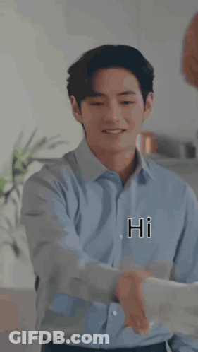 A Man In A Blue Shirt Is Shaking Hands With Another Man In A Kitchen While Smiling . GIF