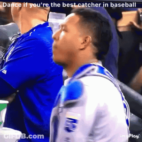 A Man In A Blue Shirt Is Sitting In A Baseball Stadium GIF