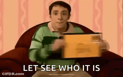 A Man In A Blue Shirt Is Sitting In A Chair Holding A Box And Saying `` Let See Who It Is `` . GIF