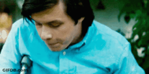 A Man In A Blue Shirt Is Sitting In A Chair . GIF