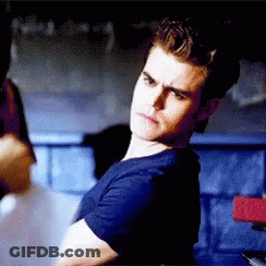 A Man In A Blue Shirt Is Sitting In A Dark Room . GIF