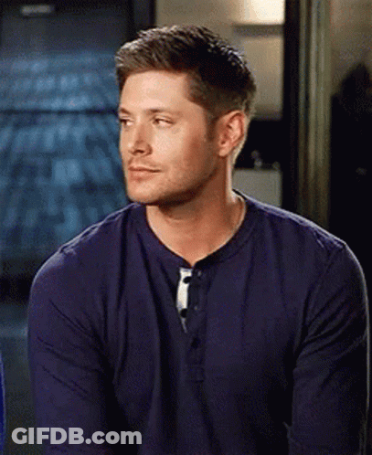 A Man In A Blue Shirt Is Sitting In A Room And Looking At The Camera . GIF