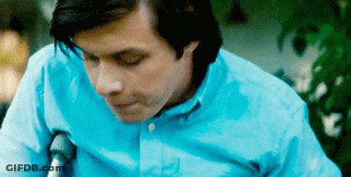 A Man In A Blue Shirt Is Sitting In A Wheelchair With Crutches . GIF