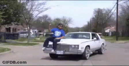 A Man In A Blue Shirt Is Sitting In A White Car GIF
