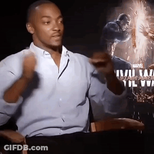 A Man In A Blue Shirt Is Sitting In Front Of A Poster For Captain America . GIF
