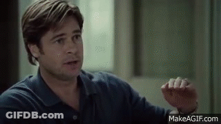 A Man In A Blue Shirt Is Sitting In Front Of A Window Talking To Someone . GIF