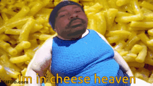 A Man In A Blue Shirt Is Sitting In Front Of Macaroni And Cheese GIF