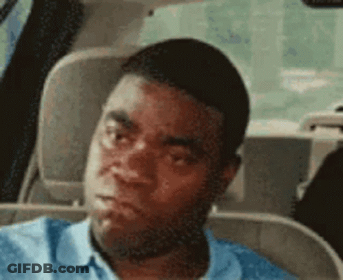 A Man In A Blue Shirt Is Sitting In The Back Seat Of A Car And Making A Funny Face . GIF