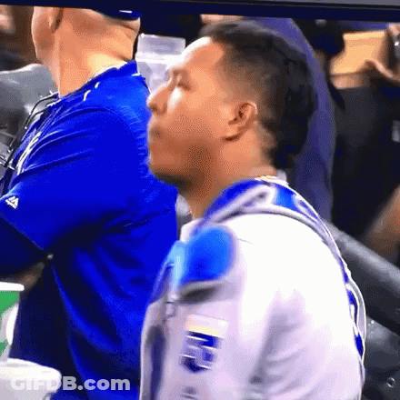A Man In A Blue Shirt Is Sitting In The Stands At A Baseball Game GIF