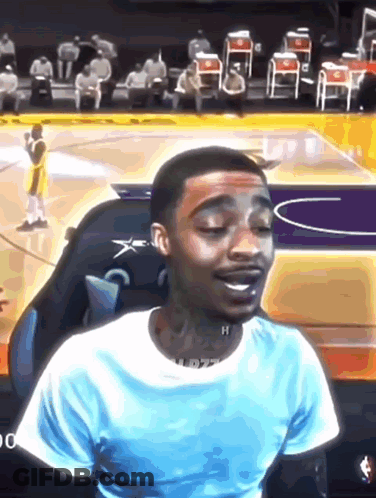 A Man In A Blue Shirt Is Sitting On A Basketball Court . GIF