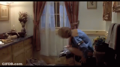 A Man In A Blue Shirt Is Sitting On A Chair In A Bathroom GIF