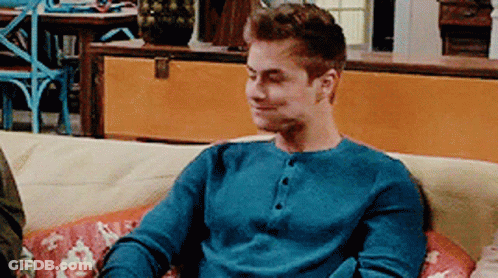 A Man In A Blue Shirt Is Sitting On A Couch GIF