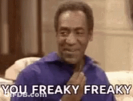 A Man In A Blue Shirt Is Sitting On A Couch And Making A Funny Face . GIF