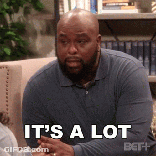 A Man In A Blue Shirt Is Sitting On A Couch And Talking To Another Man . GIF