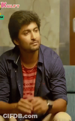 A Man In A Blue Shirt Is Sitting On A Couch With A Kulfy Logo In The Background GIF