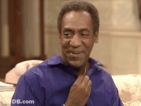 A Man In A Blue Shirt Is Sitting On A Couch With His Hand On His Chest . GIF