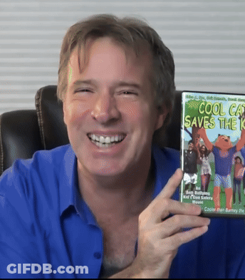 A Man In A Blue Shirt Is Smiling And Holding A Cool Cat Saves The Kid Dvd GIF
