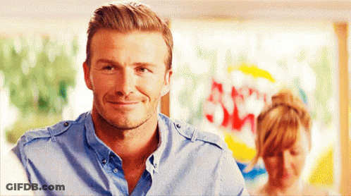 A Man In A Blue Shirt Is Smiling And Looking At The Camera GIF