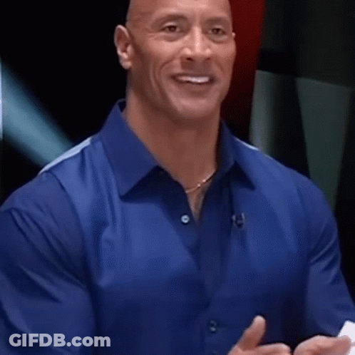 A Man In A Blue Shirt Is Smiling And Talking While Holding A Piece Of Paper . GIF