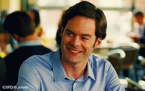 A Man In A Blue Shirt Is Smiling In Front Of A Crowd GIF