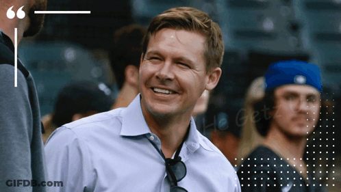 A Man In A Blue Shirt Is Smiling In Front Of A Quote GIF