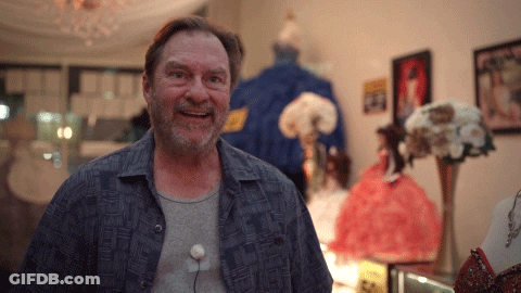 Man In Blue Shirt Smiling In Front Of A Sign GIF