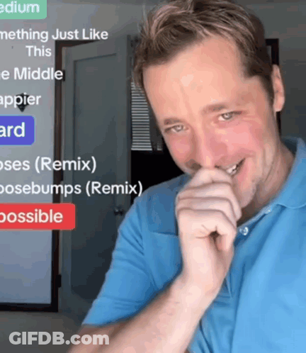 A Man In A Blue Shirt Is Smiling In Front Of A Sign That Says " Medium " GIF