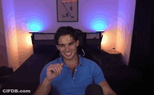 A Man In A Blue Shirt Is Smiling In Front Of A Wall With A Picture Of Golf Clubs On It GIF