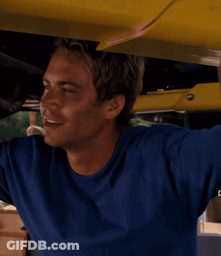 A Man In A Blue Shirt Is Smiling While Holding A Yellow Object GIF