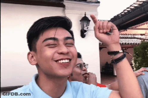 Smiling Man In Blue Shirt With Hand Up GIF
