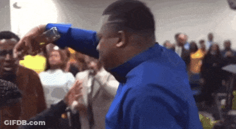 A Man In A Blue Shirt Is Standing In A Crowd GIF