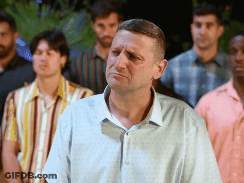A Man In A Blue Shirt Is Standing In A Crowd Of Men GIF
