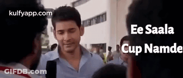A Man In A Blue Shirt Is Standing In A Crowd Of People . GIF