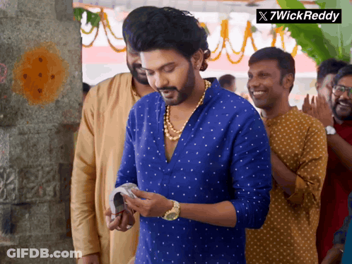 A Man In A Blue Shirt Is Standing In A Crowd With A 7Wick Reddy Logo In The Corner GIF