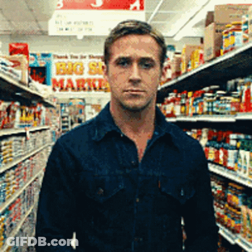 A Man In A Blue Shirt Is Standing In A Grocery Store With A Sign That Says Big Sale Market GIF