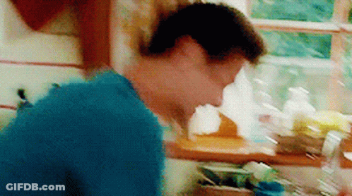 A Man In A Blue Shirt Is Standing In A Kitchen GIF