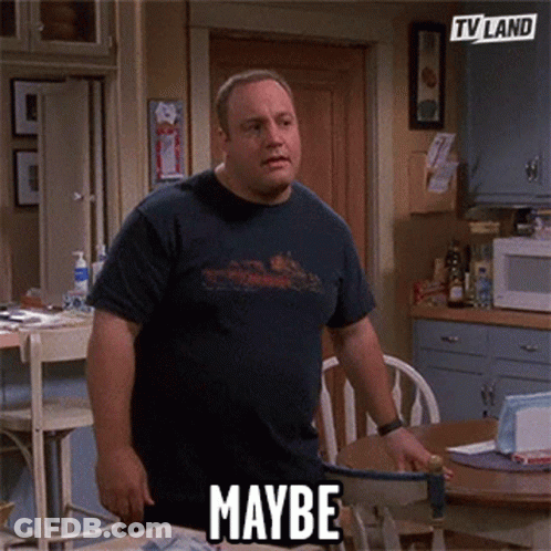 A Man In A Blue Shirt Is Standing In A Kitchen With The Word Maybe On His Shirt . GIF