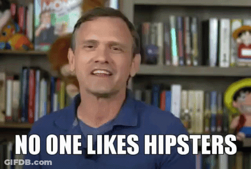 A Man In A Blue Shirt Is Standing In Front Of A Bookshelf And Says No One Likes Hipsters GIF