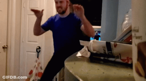 A Man In A Blue Shirt Is Standing In Front Of A Box That Says 2 Lb GIF