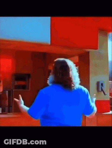 A Man In A Blue Shirt Is Standing In Front Of A Counter GIF